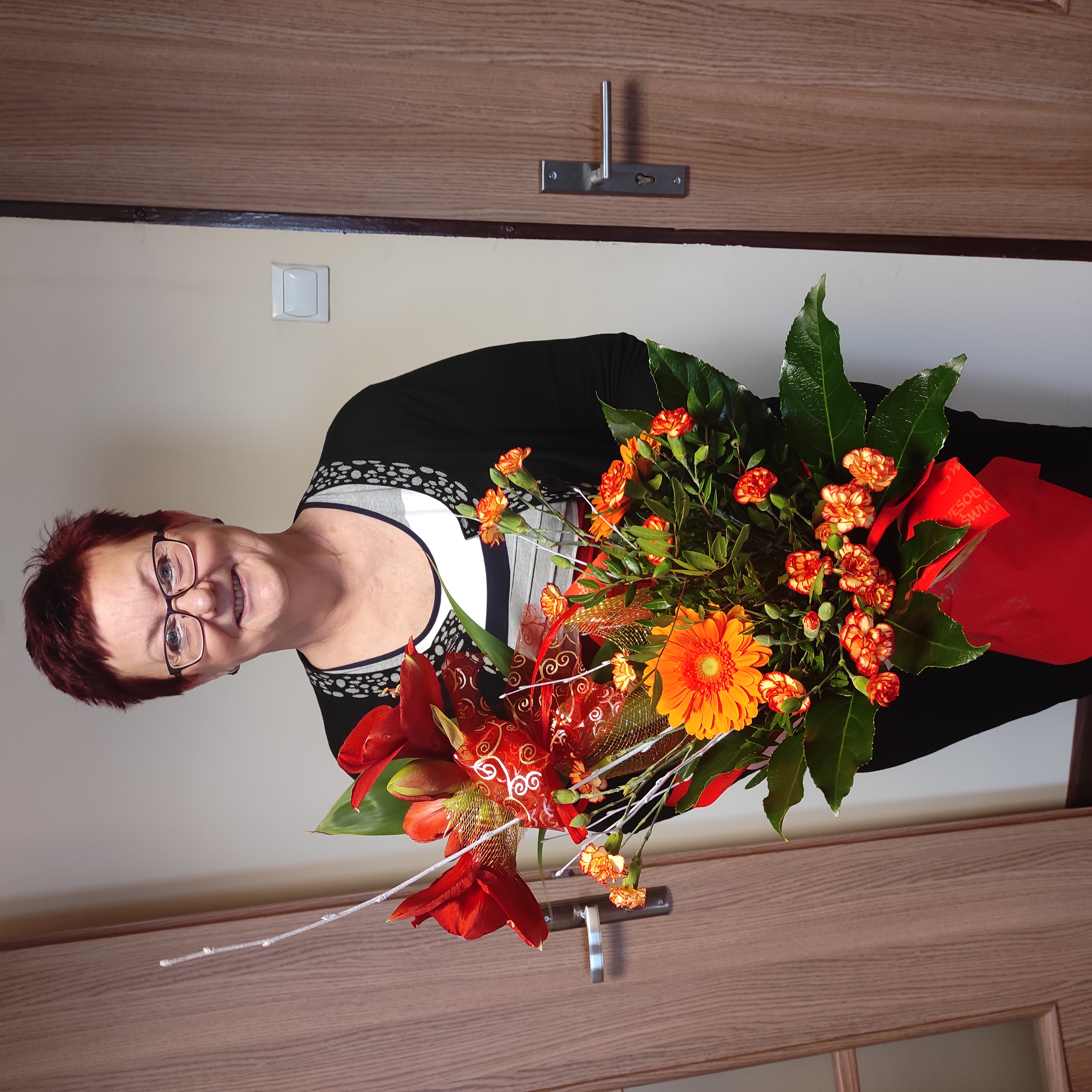 Zdjęcie przedstawia Panią Danutę z bukietem kwiatów.